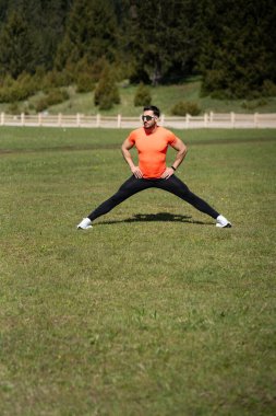 Genç adam güneşli bir günde tüm vücudu esneyerek ısınıyor.