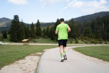 Yeşil tişört ve siyah şortla dışarıda antrenman.