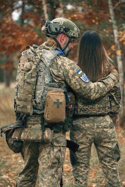 Украинские солдаты одеты в военную форму на линии фронта. Пара влюбленных в войну во время российского военного вторжения на Украину. Понятие любви, общности и поддержки. Вид сзади