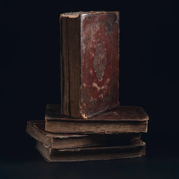 Leather bound book with gold embossing. Torah book standing on stack of old jewish books in the dark. Education and religion concept. Low key. Closeup