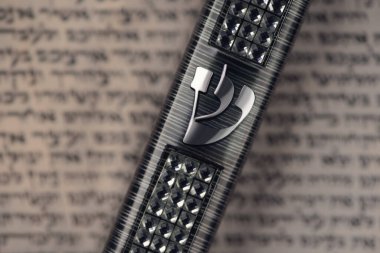 Mezuzah case laying on blurred parchment with Jewish prayer Shema Yisrael in hebrew, mezuzah commandment. Symbol of judaism. Closeup. Selective focus clipart