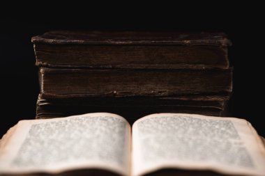 Open page with blurred hebrew religious text and old shabby leather-bound Jewish books Chumash on the background. Concept of studying and reading Torah. Selective focus. Closeup clipart