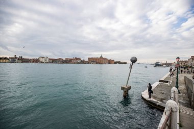 İtalya 'nın Venedik şehrinde bulutlu bir akşamda San Giorgio Maggiore' a karşı San Marco havzasında demirlemiş geleneksel gondollar.