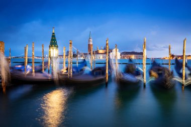 İtalya 'nın Venedik şehrinde bulutlu bir akşamda San Giorgio Maggiore' a karşı San Marco havzasında demirlemiş geleneksel gondollar.