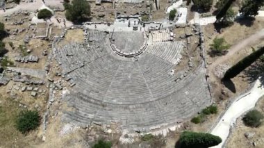 Delphi, Phocis / Yunanistan. Delphi Antik Tiyatrosu. 5.000 seyirci kapasiteli tiyatro Apollo 'nun sığınağında yer almaktadır. Güneşli bir günde bulutlu bir gökyüzü ile panoramik manzara