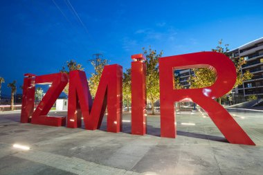 Red three-dimensional 3d letters containing the word IZMIR in the clear sky at evening time. clipart