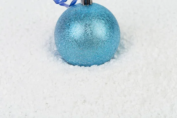 青いリボンの上の青いクリスマスボール 人工雪の上にあります — ストック写真