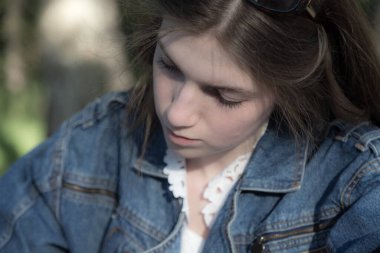 Güzel bir kız bir şeyler yazıyor. Parkta bir yerde oluyor. Yakın plan..