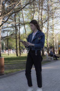 Elinde kitap olan güzel bir kızın portresi. Parkta bir yerde oluyor. Yakın plan..