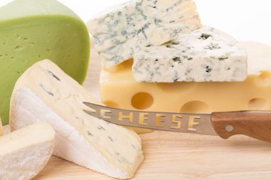 Tahta bir tabakta farklı peynirler seti. Beyaz bir yüzey üzerinde yer alır. Yakın plan..