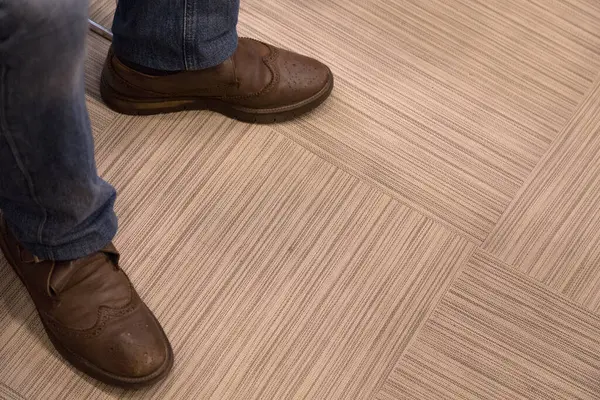 Men's feet in casual walking shoes. The surface is made of ceramic tiles. Close-up.