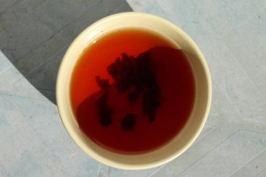 Siyah çay ile Çin çay fincanı. Bir ışık demeti fincanı aydınlatır. Yakın plan..