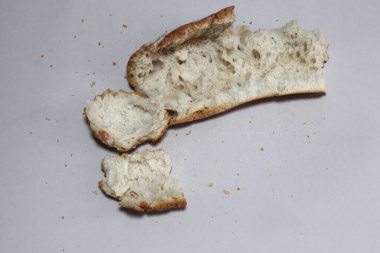 Kırık, yeni pişmiş bir ekmek. Gri bir arka planda yer almaktadır. Yakın plan..