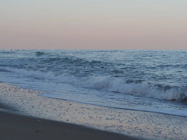 ピンク色の空をした砂浜の波 — ストック写真