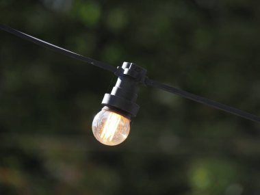 A garland of LED lights with a transparent bulb on a sky background is turned on