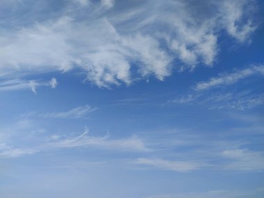 Mavi gökyüzünde rüzgarın savurduğu şeffaf bulutlar.