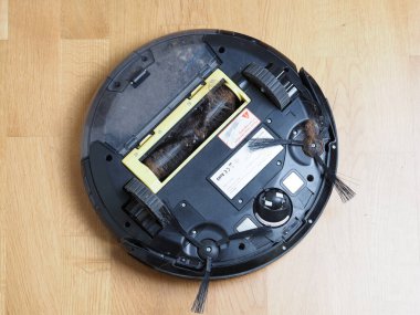 Evin zeminini temizledikten sonra fırça robotu elektrikli süpürgesine sarılmış uzun kadın saçı.