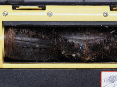 Evin zeminini temizledikten sonra fırça robotu elektrikli süpürgesine sarılmış uzun kadın saçı.