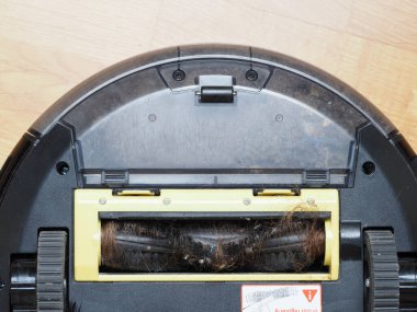 Evin zeminini temizledikten sonra fırça robotu elektrikli süpürgesine sarılmış uzun kadın saçı.