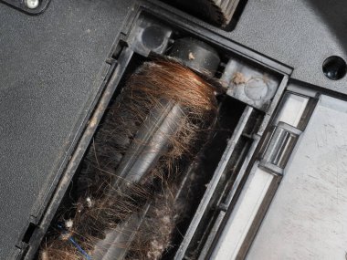 Evin zeminini temizledikten sonra fırça robotu elektrikli süpürgesine sarılmış uzun kadın saçı.