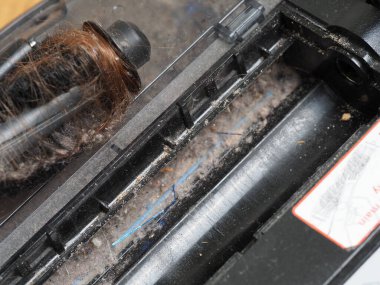 Evin zeminini temizledikten sonra fırça robotu elektrikli süpürgesine sarılmış uzun kadın saçı.