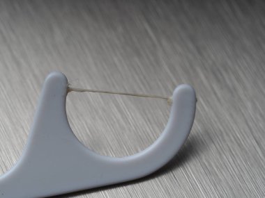 Metal arka planda ferahlatıcı diş ipiyle yakın plan kürdanı