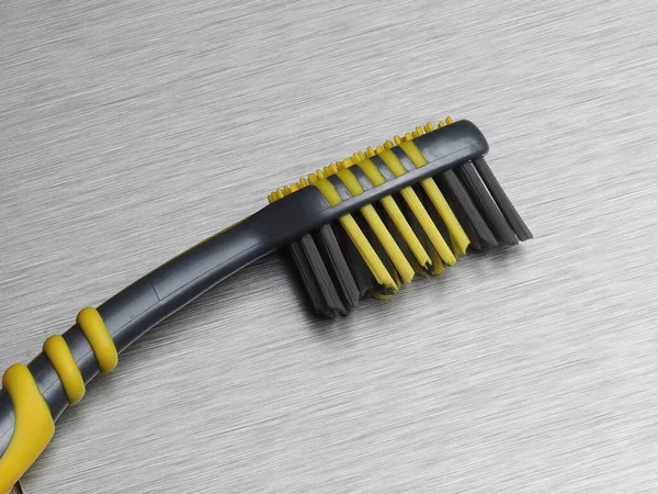 Graue Zahnbürste Mit Schwarzen Und Gelben Borsten Auf Einem Metallhintergrund — Stockfoto