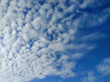 Mavi gökyüzü güneşle aydınlanır birkaç beyaz bulutla