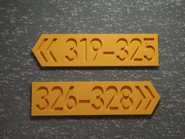 Gri arka planda sarı işaretler. Gri arka planı olan bir ofis binasının duvarında. Duvarda tahta tabela var, metin için yer var.