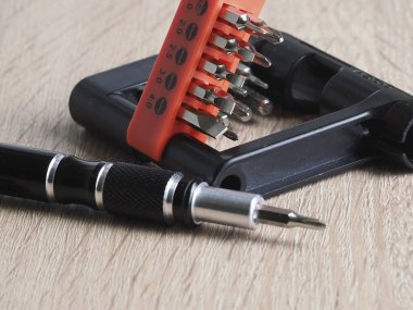 Bir tornavida ve ahşap masadaki elektronik eşyaları tamir etmek için birkaç parça.