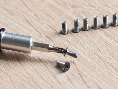 Açık tahta arka planda vida ve tornavida yakın plan