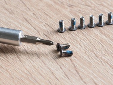 Açık tahta arka planda vida ve tornavida yakın plan