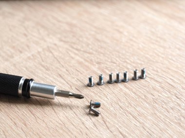 Açık tahta arka planda vida ve tornavida yakın plan