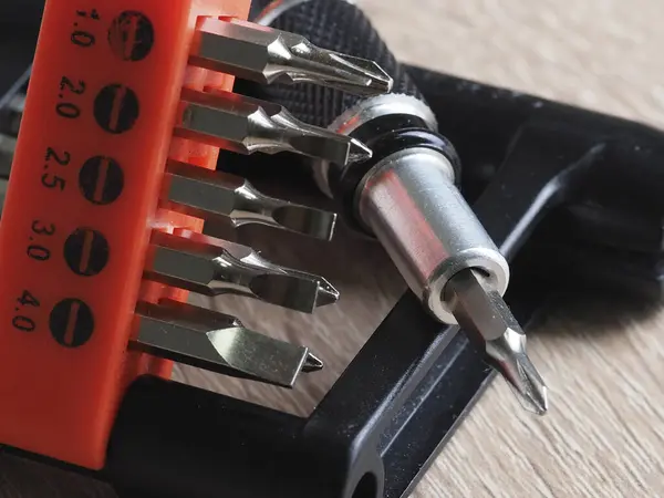 Bir tornavida ve ahşap masadaki elektronik eşyaları tamir etmek için birkaç parça.