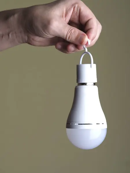 turned off LED rechargeable lamp in human hands on beige background
