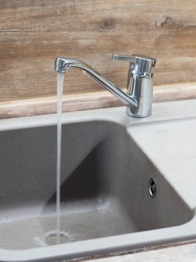 Ahşap bir duvarın arkasında su olan musluk.