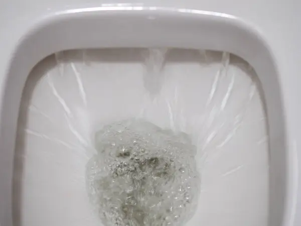 Draining water into a white ceramic toilet bowl
