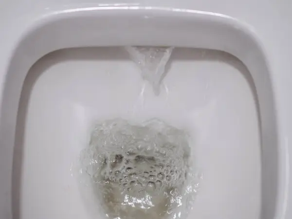 Draining water into a white ceramic toilet bowl