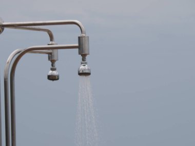 Bulutlu bir gökyüzünün altında kumsalda açık bir duş.