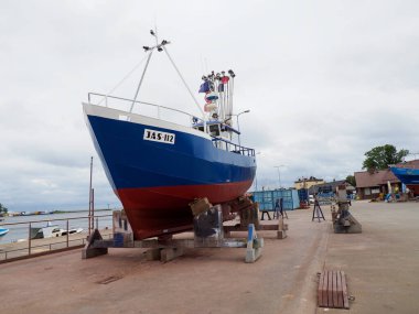 Large Blue Fishing Vessel on Dock Under Cloudy Sky clipart