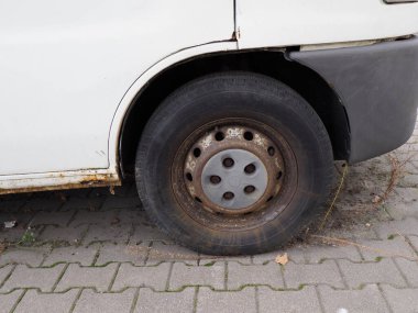 Kaldırımda paslı tekerleği olan eski beyaz bir araba.