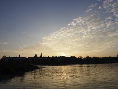 Ufuk ve Su Yansımaları Üzerine Şehir Silueti ile Nehrin Üzerinde Gün Batımı