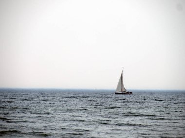 Ufuktaki yelkenli Gri gökyüzünün altında sakin denizde