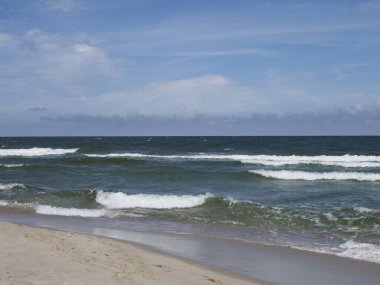 Kumsalda dalgalar ve ufukta mavi gökyüzü