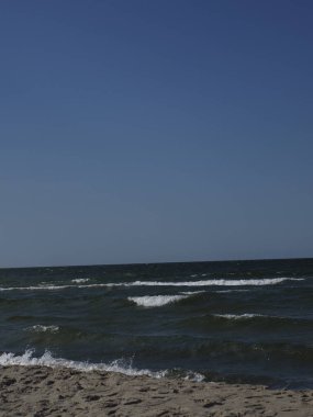 Dalgalar ve ufukta mavi gökyüzü olan sahil manzarası