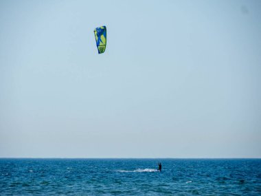 Güneşli bir günde gökyüzünde renkli bir uçurtmayla sörf yapan uçurtma sörfçüsü
