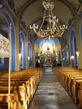 Süslü ahşap sıraları ve avizeleri olan tarihi bir kilisenin güzel aydınlatılmış iç kısımları.