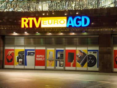 RTV Euro AGD elektronik mağazasının gece renkli tabelaları ve ürün reklamlarıyla aydınlatılmış vitrinleri