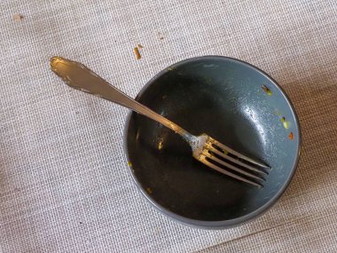 Yemekten sonra çatallı bir masa örtüsü olan boş bir kâse, yemek artıklarını gösteriyor.