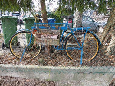 Yeşil Kutular ve Ağaçlarla Çitlerin Arkasında Eski Mavi Bisiklet